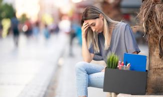 Eine junge Frau sitzt auf einer Bank mit einer Kiste Arbeitsmaterialien