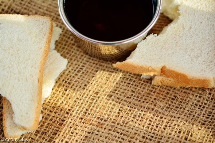 Bächer Wein mit Brot auf einem Tuch mit Kreuzzeichen 