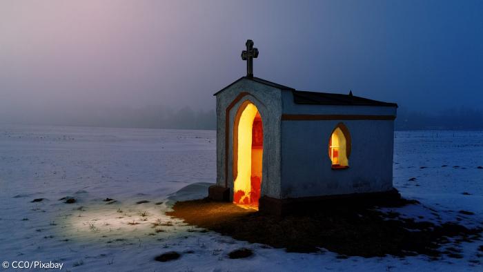Von innen beleuchtete Kapelle in einer Schneelandschaft