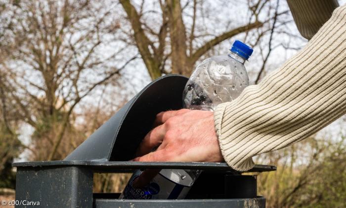 Eine Person nimmt eine Pfandflasche aus dem Mülleimer. Ein Symbolbild für Armut