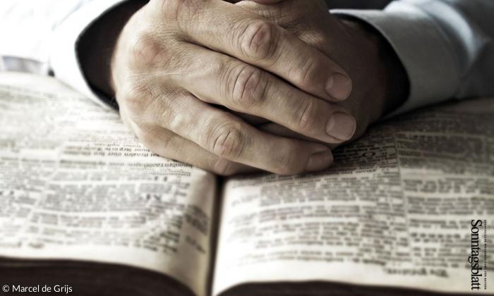 Gefaltete Hände über einer Bibel
