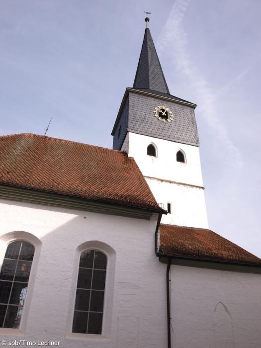 Die Außenfassade der Evangelischen Kirche Weisendorf. Man sieht den Kirchturm und zwei unterschiedlich hohe, schräge Dächer. 