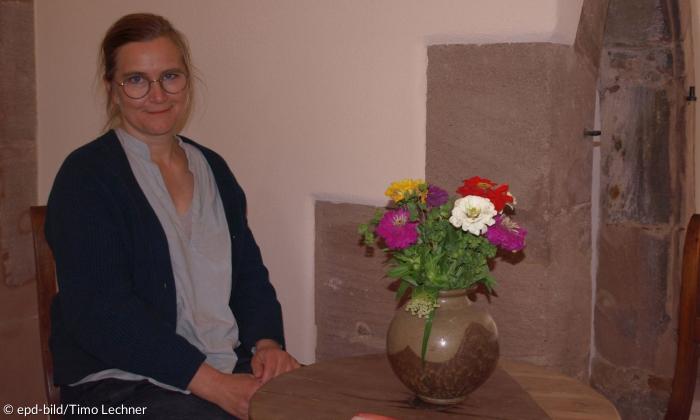 Melanie Stummhöfer sitzt an einem Tisch mit einer Blumenvase.