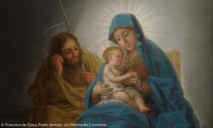 Maria hält das Jesuskind im Arm. Josef sitzt neben ihr. Beide schauen auf das Kind.