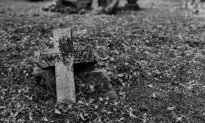 Grabstein in Form eines Kreuzes steckt in der Erde