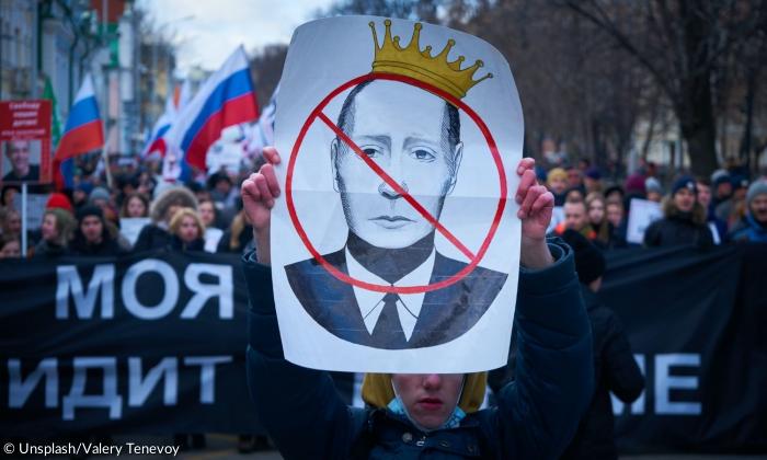 Ein Demonstrant hält ein Bild von Putin, auf dem dieser durchgestrichen ist