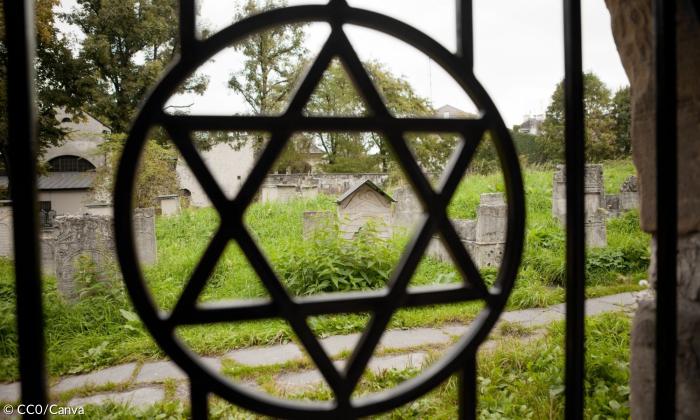 Ein Tor zu einem jüdischen Friedhof mit dem Davidstern, dahinter Gräber
