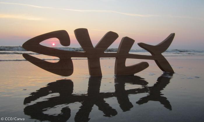 Die Buchstaben S, Y, L und T am Strand, dahinter Sonnenuntergang
