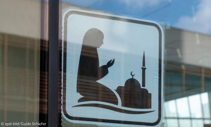 Ein Sticker zeigt eine betende Frau vor einer Moschee