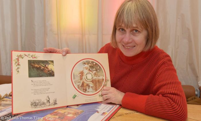 Eine Frau zeigt ein Buch mit Weihnachtsmotiven in die Kamera