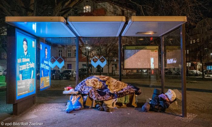 Eine obdachlose Person an einer Bushaltestelle bei Nacht