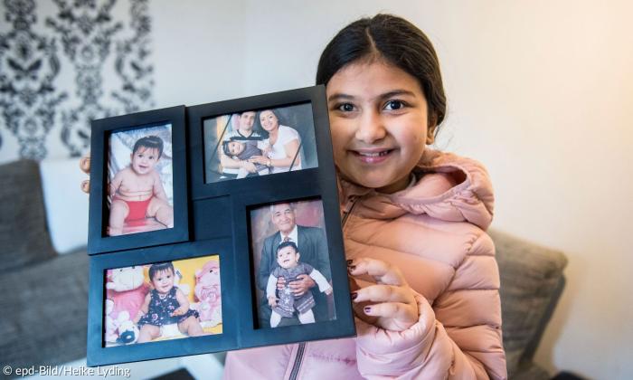 Ein Mädchen zeigt Fotos von Verwandten