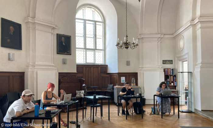 Vier Studieremde sitzen mit Laptops ans Schreibtischen in der Chorkapelle. 