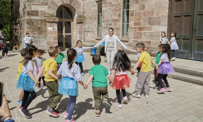 Kinder und eine Frau bilden einen Kreis 