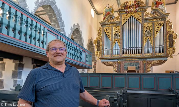 Kirchenpfleger Rainer Schülein mit der Orgel in der Kirche in Aufkirchen