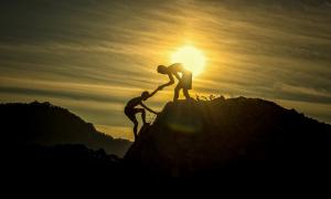 Zwei Jungen helfen sich gegensetig einen Berg zu erklimmen 