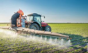 Traktor versprüht Pestizide auf Feld.