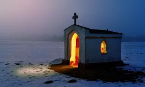 Von innen beleuchtete Kapelle in einer Schneelandschaft