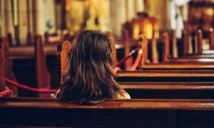 Eine Frau sitzt in der Kirche (Symbolbild)