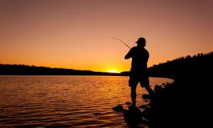 Fischer mit Angel im Abendlicht