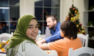 Eine muslimische Frau sitzt vor einem christlichen Weihnachtsbaum