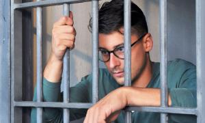 Ein Mann mit Brille hinter Gitterstäben