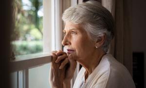 Eine Frau mit grauen Haaren schaut aus dem Fenster