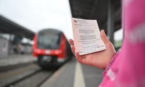 Ein 9-Euro-Ticket, im Hintergrund eine Bahn am Bahnsteig