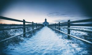 Ein schneebedeckter Weg führt zu einer kleinen Kirche
