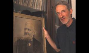 Universitätsmusikdirektor Konrad Klek mit dem Porträt Johann Georg Herzogs vor seinem Bücherschrank im Erlanger Büro.