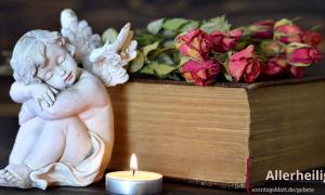 Ein Engel, eine Kerze, Rosen und die Bibel liegen auf dem Tisch 