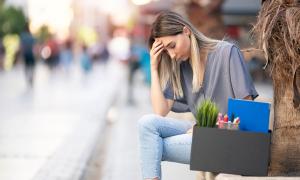Eine junge Frau sitzt auf einer Bank mit einer Kiste Arbeitsmaterialien