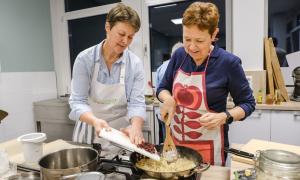 Zwei Frauen mit Schürzen beim Kochen