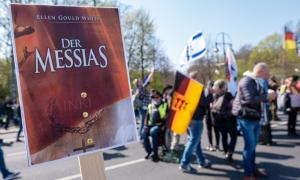 Menschen mit Fahnen, davor ein Plakat, auf dem "Der Messias" steht