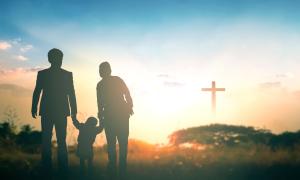 Eine Familie vor einem Kreuz