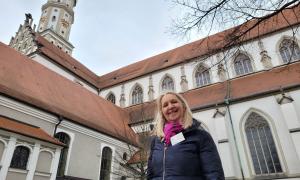 Gästeführerin Renate Braun zwischen den beiden Augsburger Kirchen, die dem Heiligen Ulrich gewidmet sind: der katholischen Basilika St.Ulrich und Afra und der evangelischen St. Ulrichkirche.