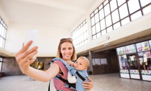 Eine Frau mit einem Baby auf dem Arm macht ein Selfie