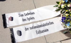 Auf zwei am Boden ausgebreiteten Bannern steht: "Zum Gedenken an den Opfern der nationalsozialistischen Euthanasie"