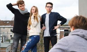 Ein Jugendlicher filmt drei andere mit dem Handy, diese posen