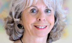 Eine Frau mit weiß-grauen Haaren lächelt in die Kamera