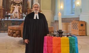 Pfarrer mit Regenbogenfahne in der Kirche