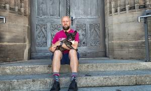 Ein Mann mit Hund auf dem Arm vor einer Kirchentür