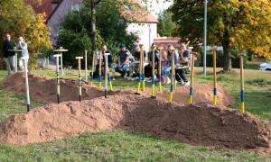 Spaten stecken in kreuzförmig angeordneten Erdhügeln
